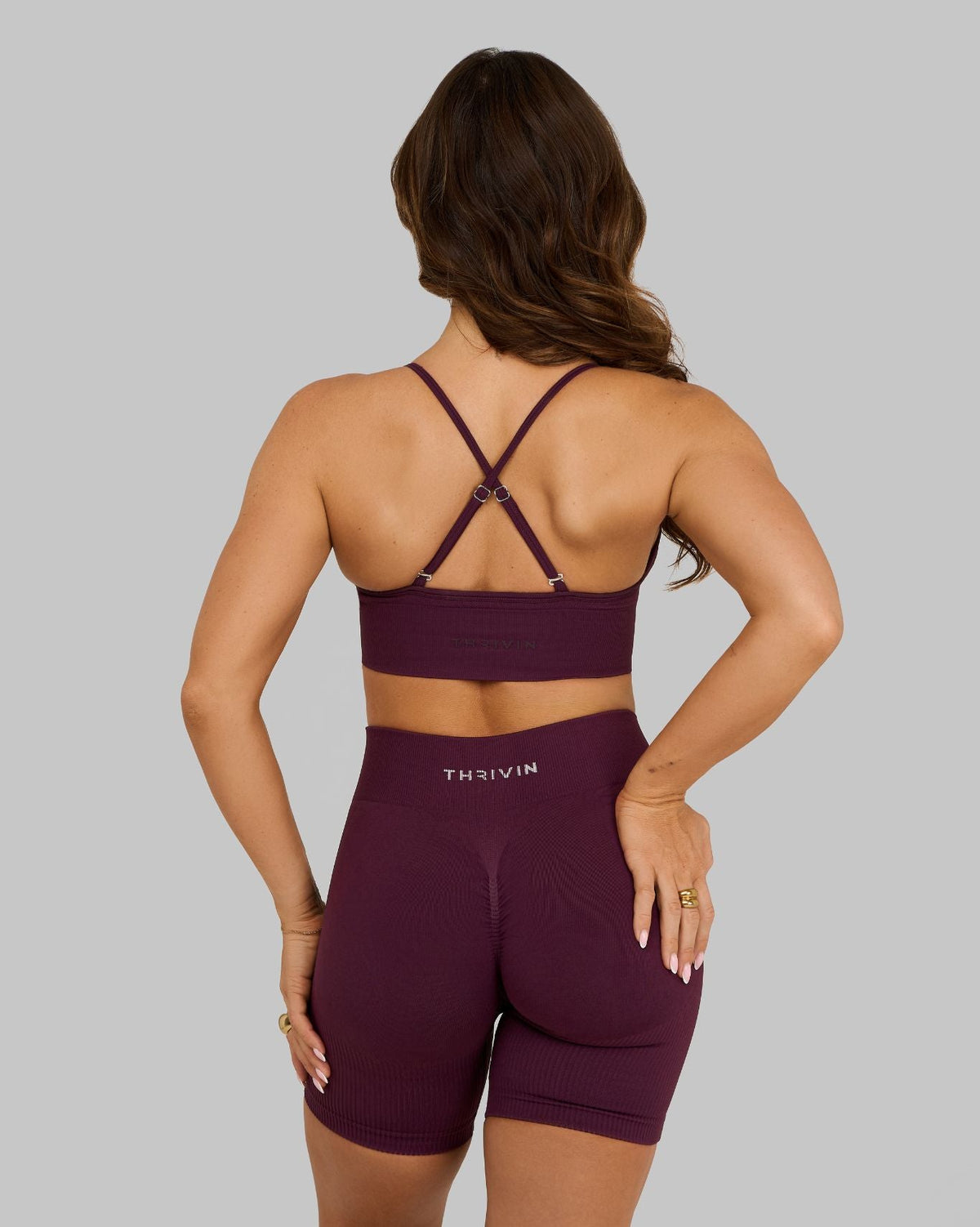 Elevate Multiway Sculpt Seamless Bra in Winter Plum Red, back view with hands on hips, thin crossed straps