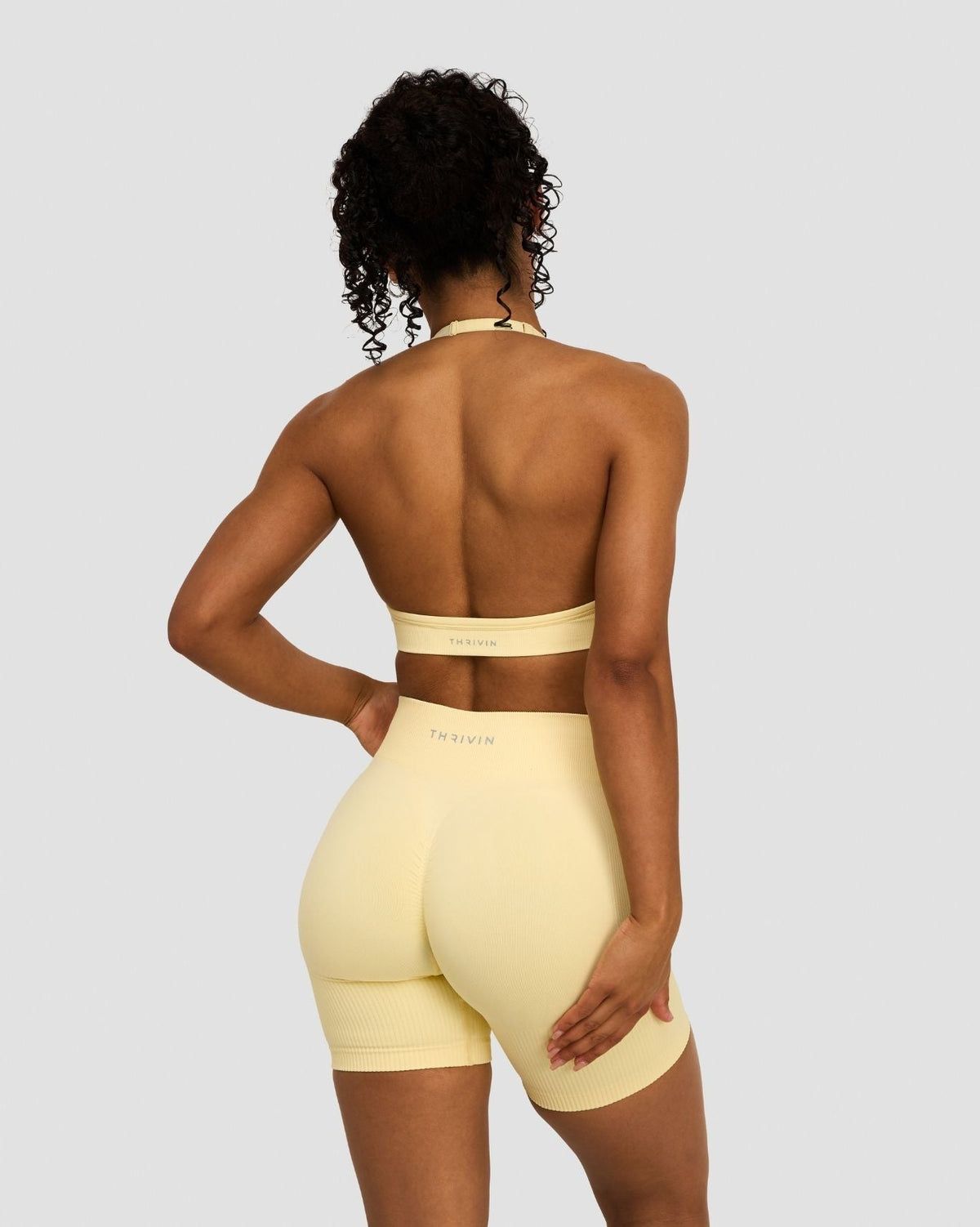 Elevate Sculpting Seamless Adjustable Halter Bra in Butter Yellow, back view with halter ties and band, styled with shorts