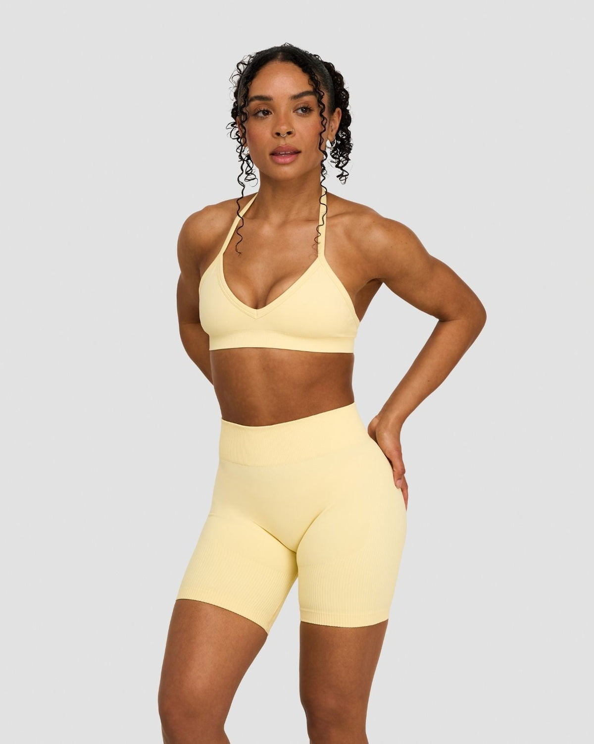 Elevate Sculpting Seamless Adjustable Halter Bra in Butter Yellow, front view with hand on hip, styled with matching shorts