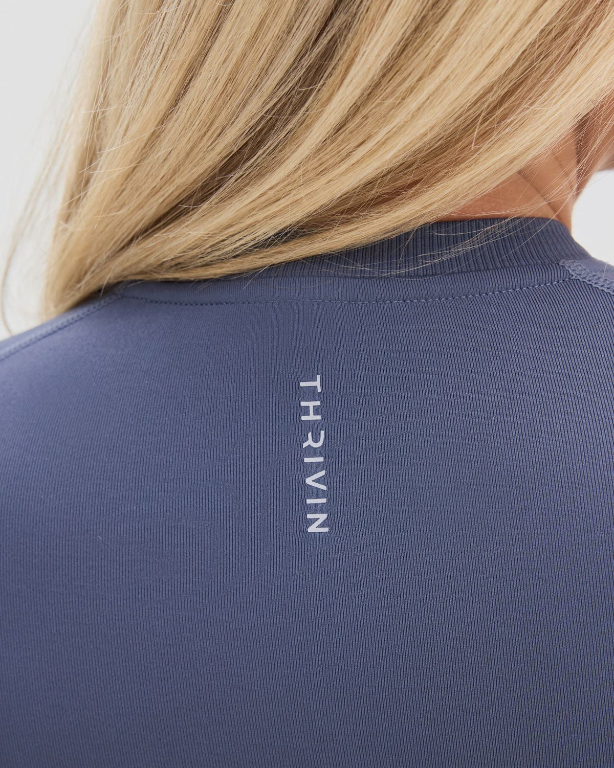 Elevate Compression T-Shirt in Steel Blue, back close-up of ribbed neckline and vertical Thrivin logo on fine ribbed knit