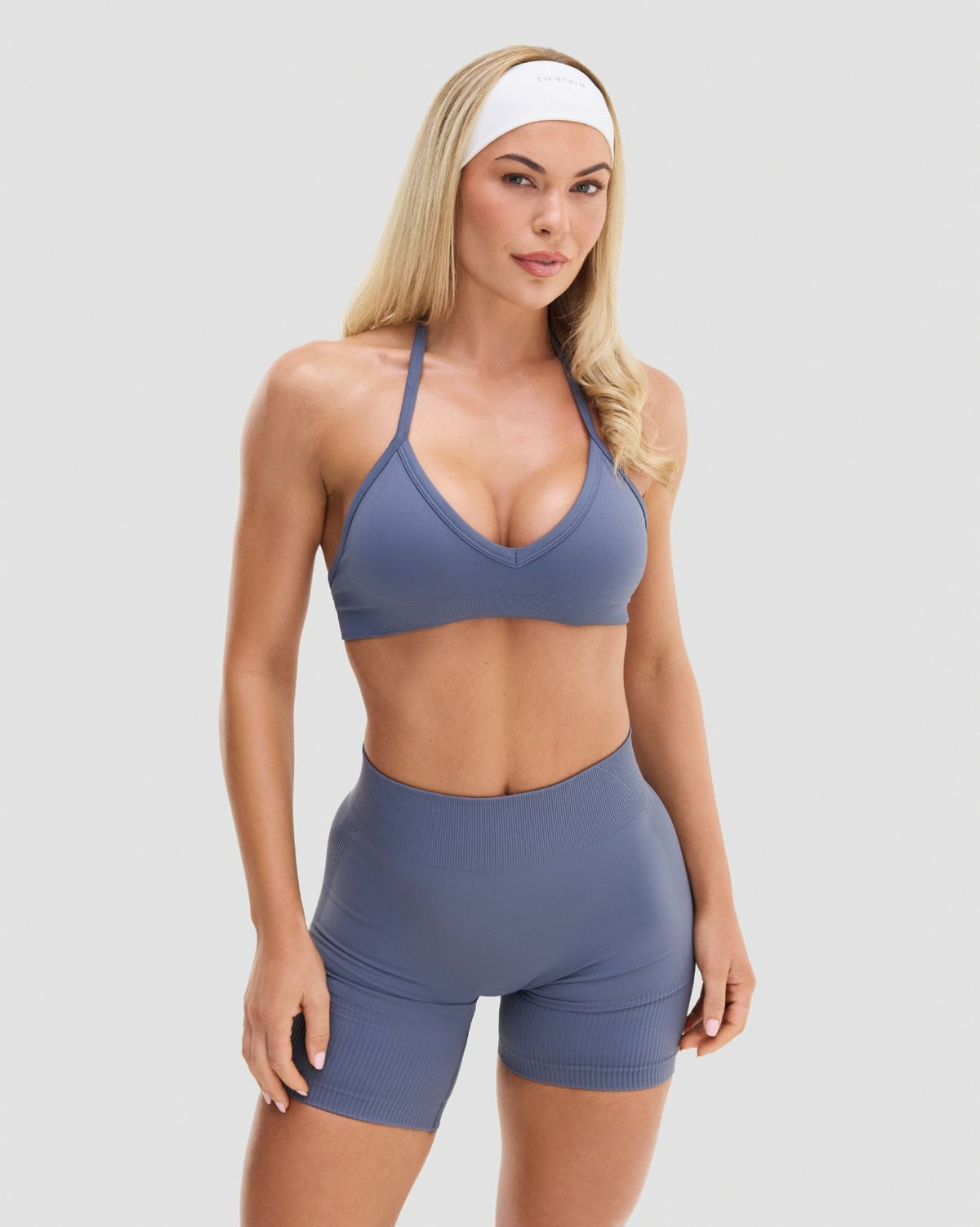 Elevate Sculpting Seamless Adjustable Halter Bra in Steel Blue, front view of V-neckline and halter neck with gym shorts