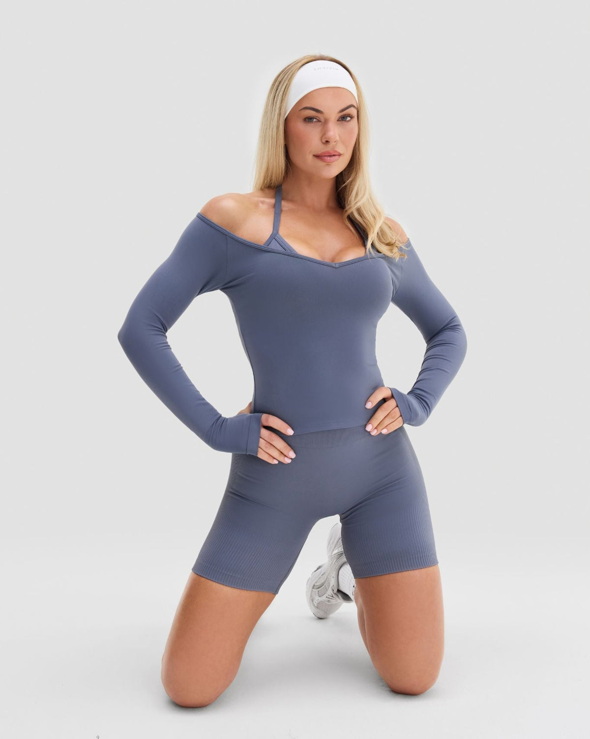 Elevate Sculpting Seamless V-Neck Top in Steel Blue, kneeling front view of off-shoulder neckline with gym shorts